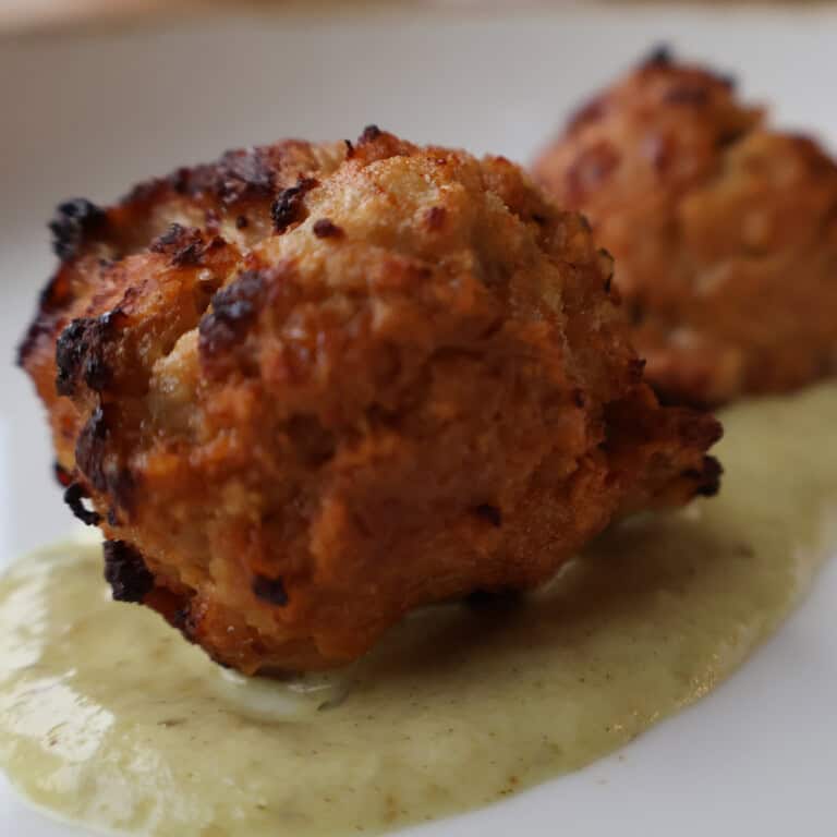 Mini chipotle BBQ chicken meatballs glazed in smoky sauce and over cilantro sauce.