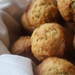 Mini banana bread muffins piled in a bowl covered with a kitchen towel.