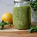 Basil walnut pesto in a mason jar with fresh basil and lemon