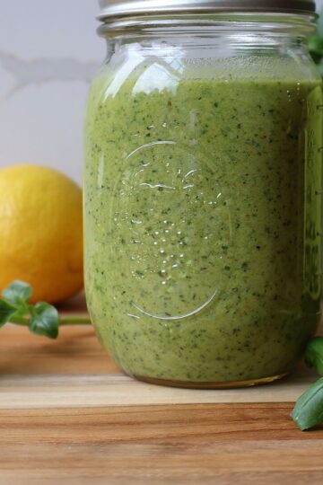 Basil walnut pesto in a mason jar with fresh basil and lemon