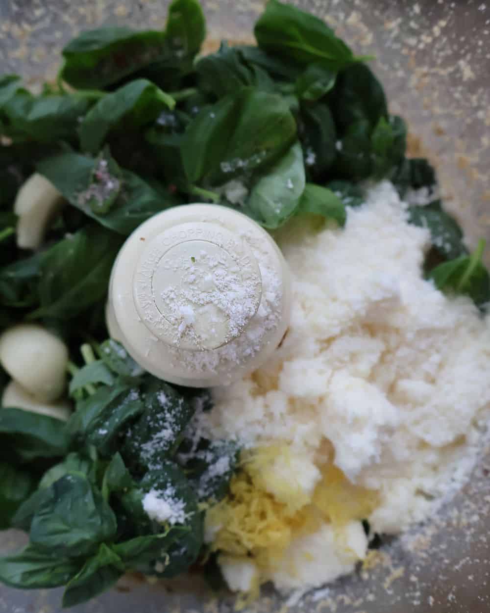 Fresh basil, grated Parmesan cheese, and garlic cloves added to the food processor with pulsed walnuts