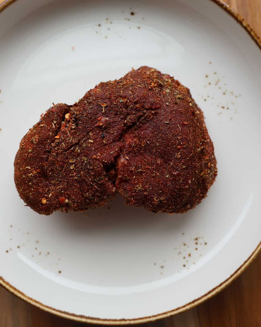 two filet mignon steaks coated in blackening seasoning on a white plate