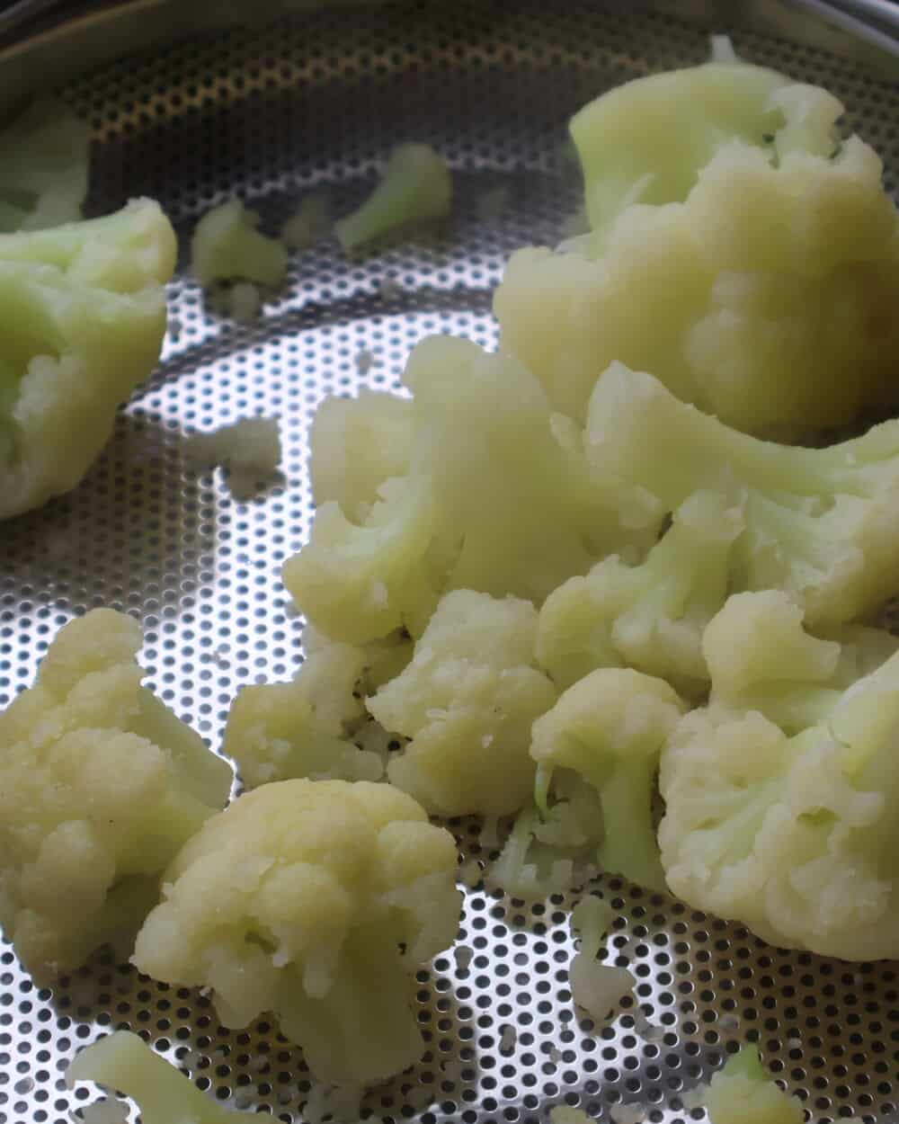 tender steamed cauliflower florets in a stainless steel colander
