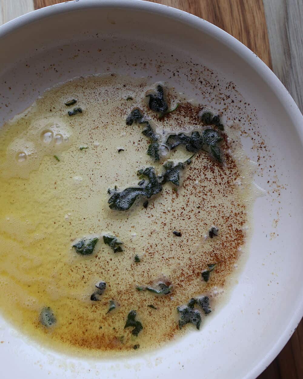 sage brown butter with crispy sage leaves toasting in a white pan