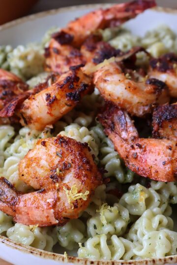 Overhead view of blackened shrimp on basil walnut pesto pasta