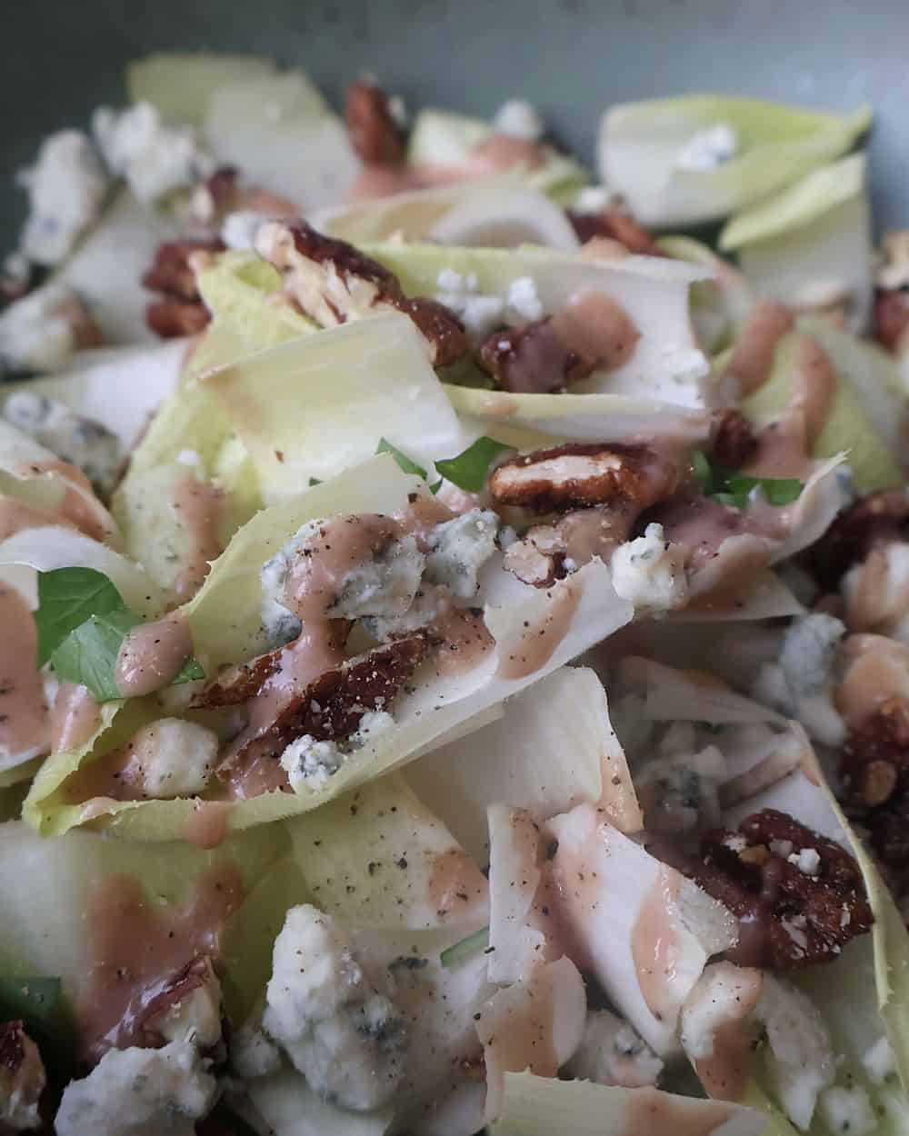 Finished endive salad tossed with strawberry balsamic dressing, Gorgonzola, and spiced pecans
