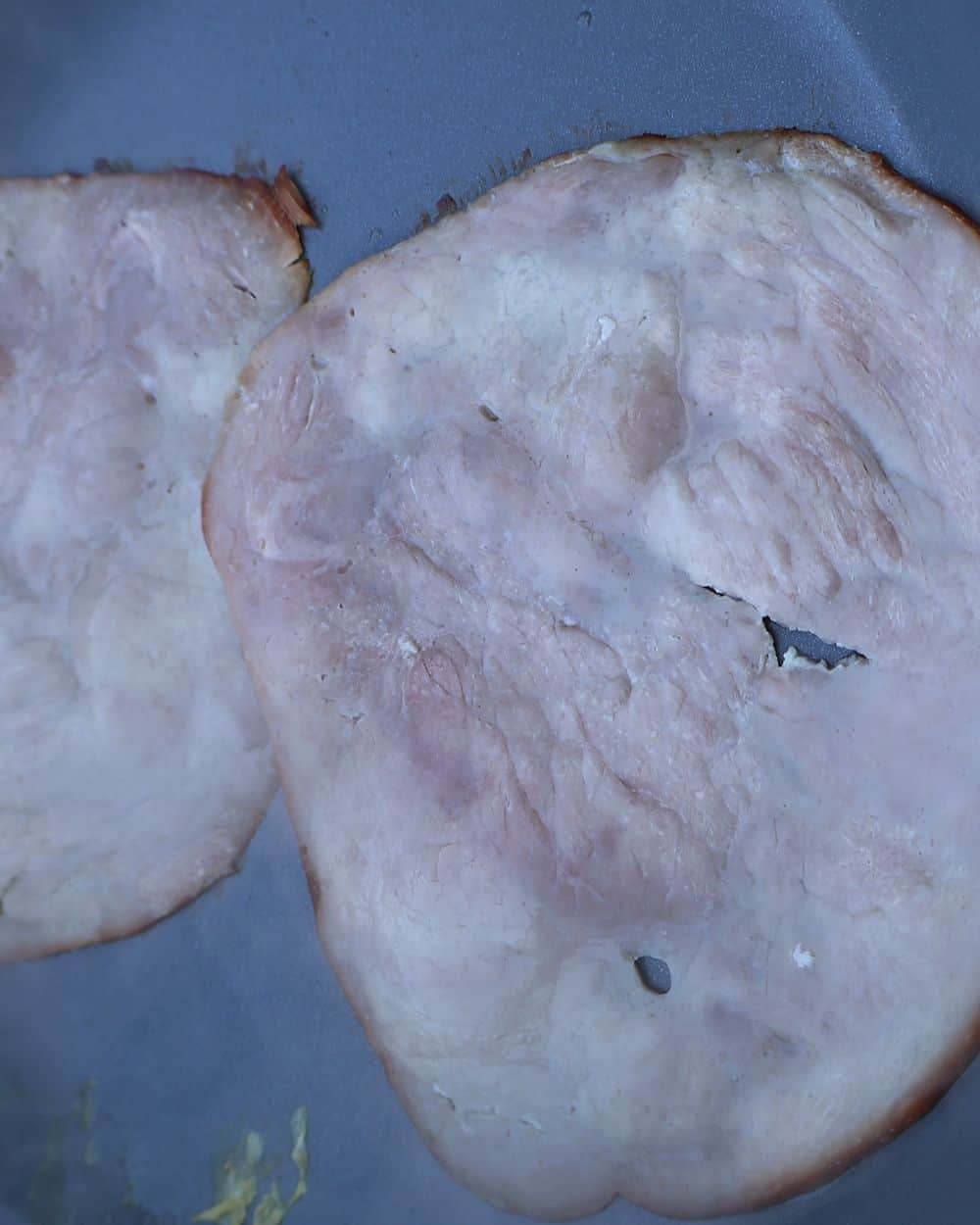 Ham slices browning in a skillet until golden and crispy