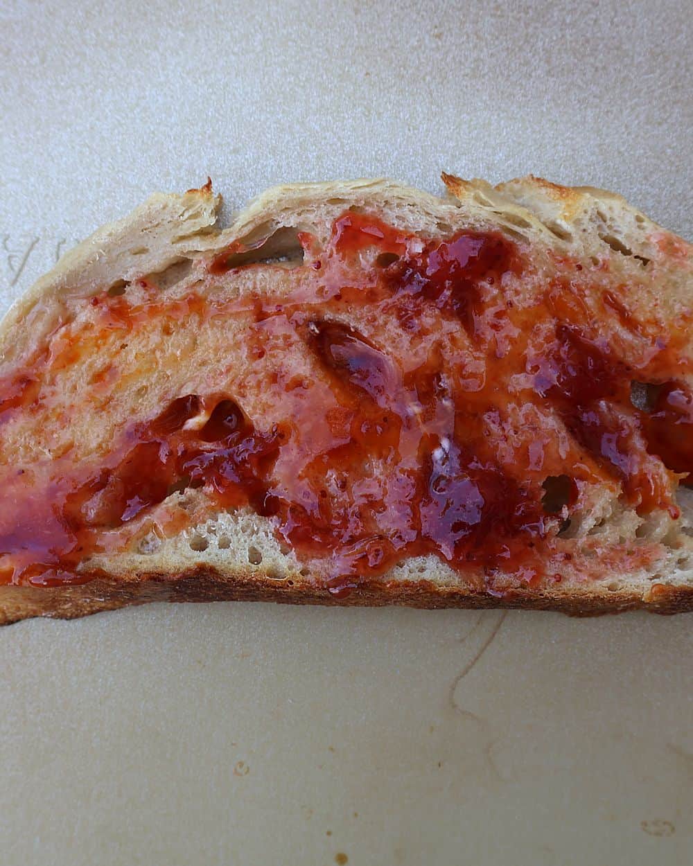 Strawberry jelly spread on a slice of toasted sourdough bread