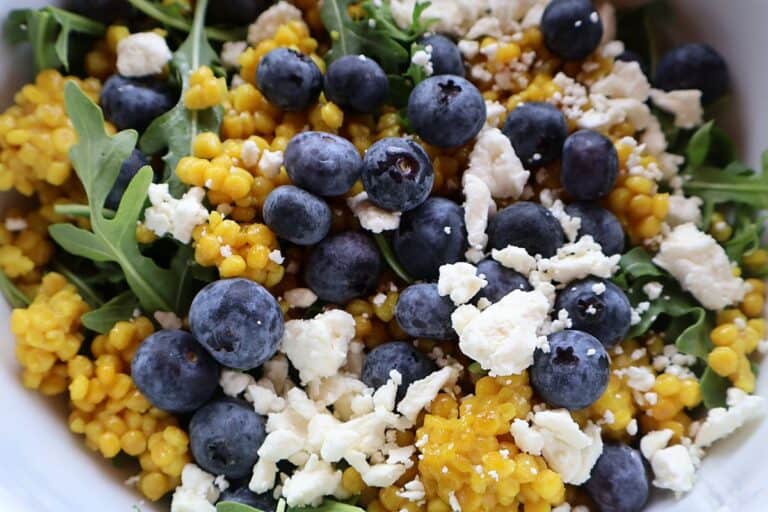 Israeli couscous salad with blueberries, arugula, and feta cheese in a bowl