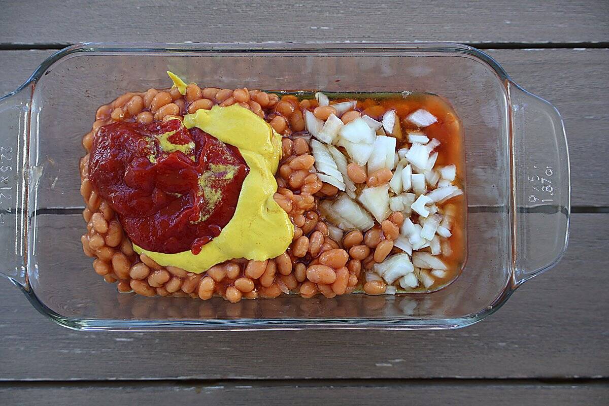 Whisking maple syrup, ketchup, and yellow mustard sauce in a glass bowl
