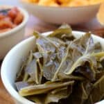Collard greens with ham hocks served in a white bowl - featured image