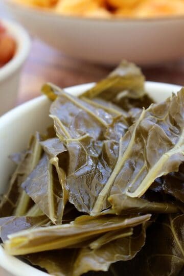 Collard greens with ham hocks served in a white bowl - featured image