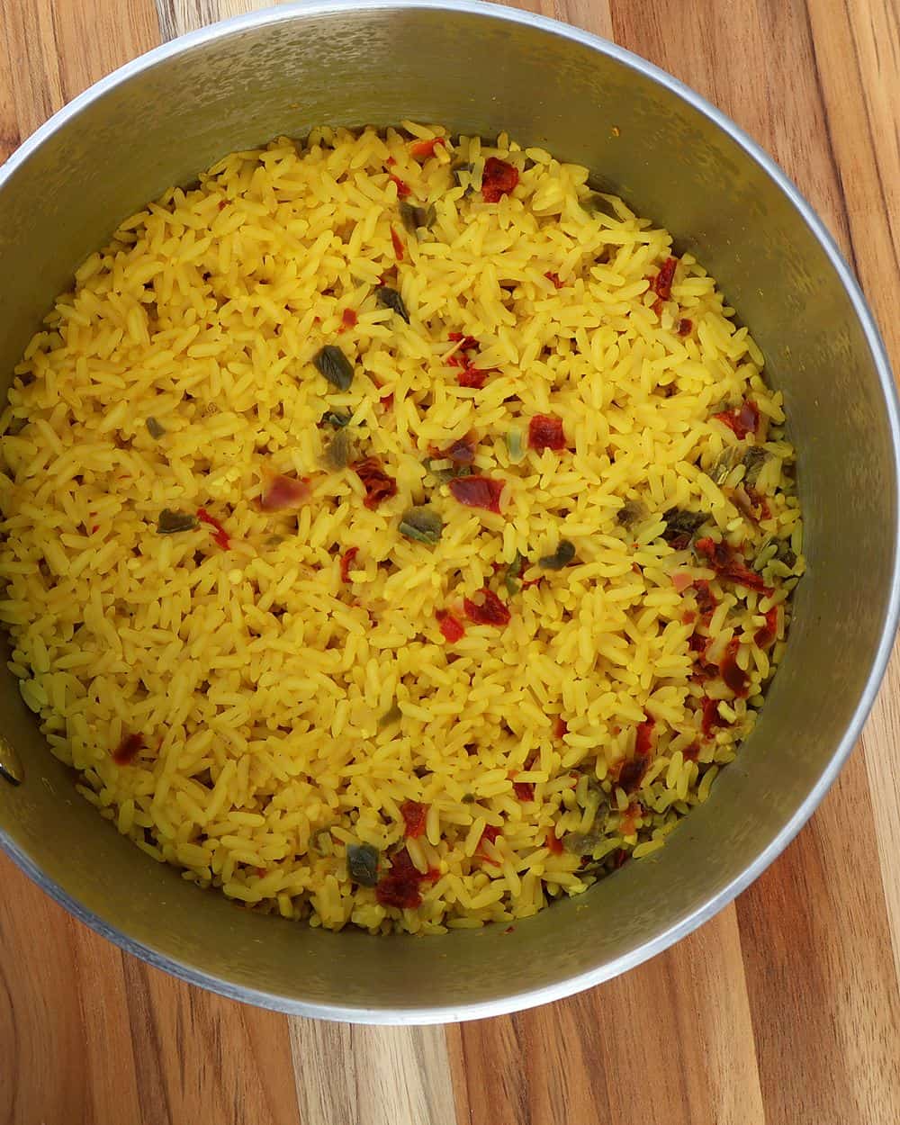 Yellow rice cooking in a pot with a fork for fluffing