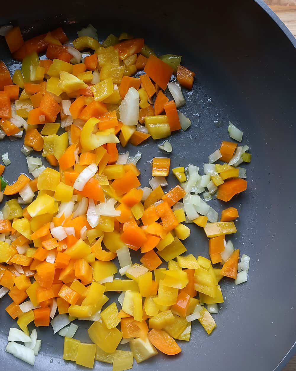 Sautéing red and yellow bell peppers and onions in a skillet