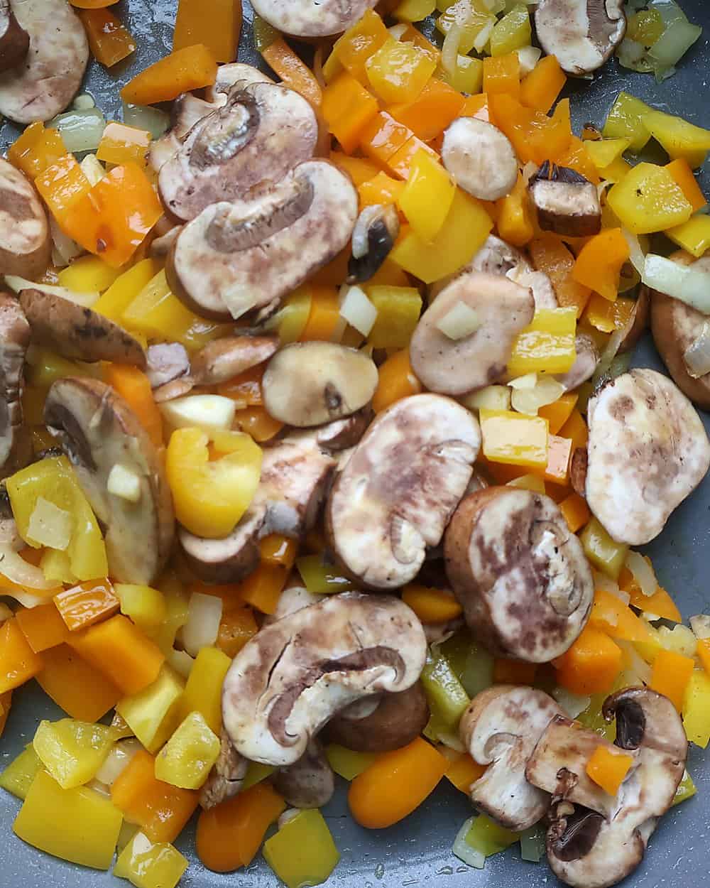 Adding sliced mushrooms and minced garlic to the skillet