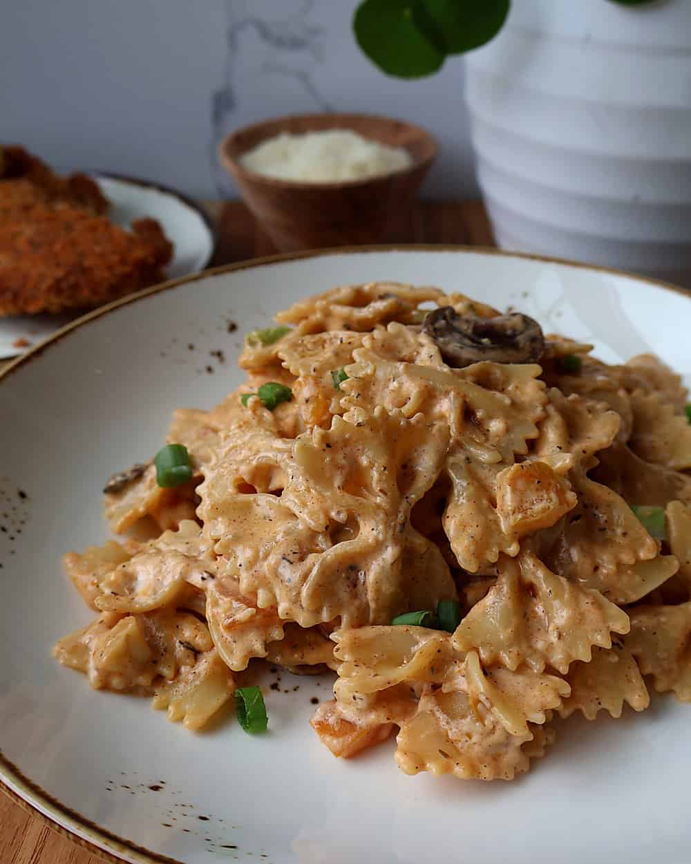 Bowl of Louisiana chicken pasta topped with sliced parmesan tenders and chives