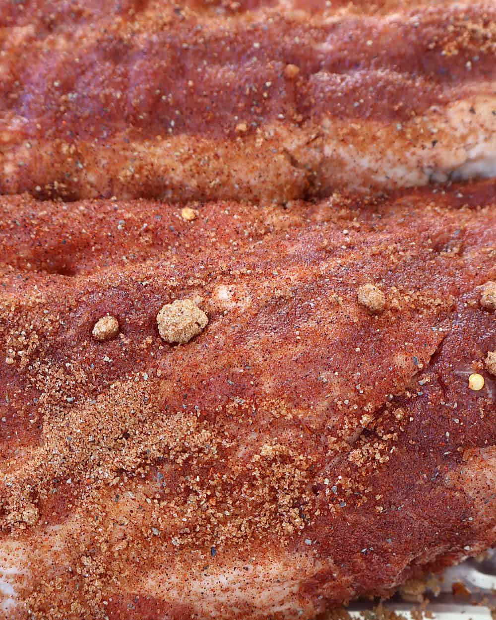 Baby back ribs generously coated with brown sugar spice rub in a deep baking tray