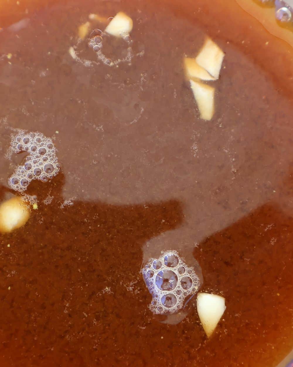 Pouring cola and coffee braising liquid into the corner of the baking tray with seasoned ribs