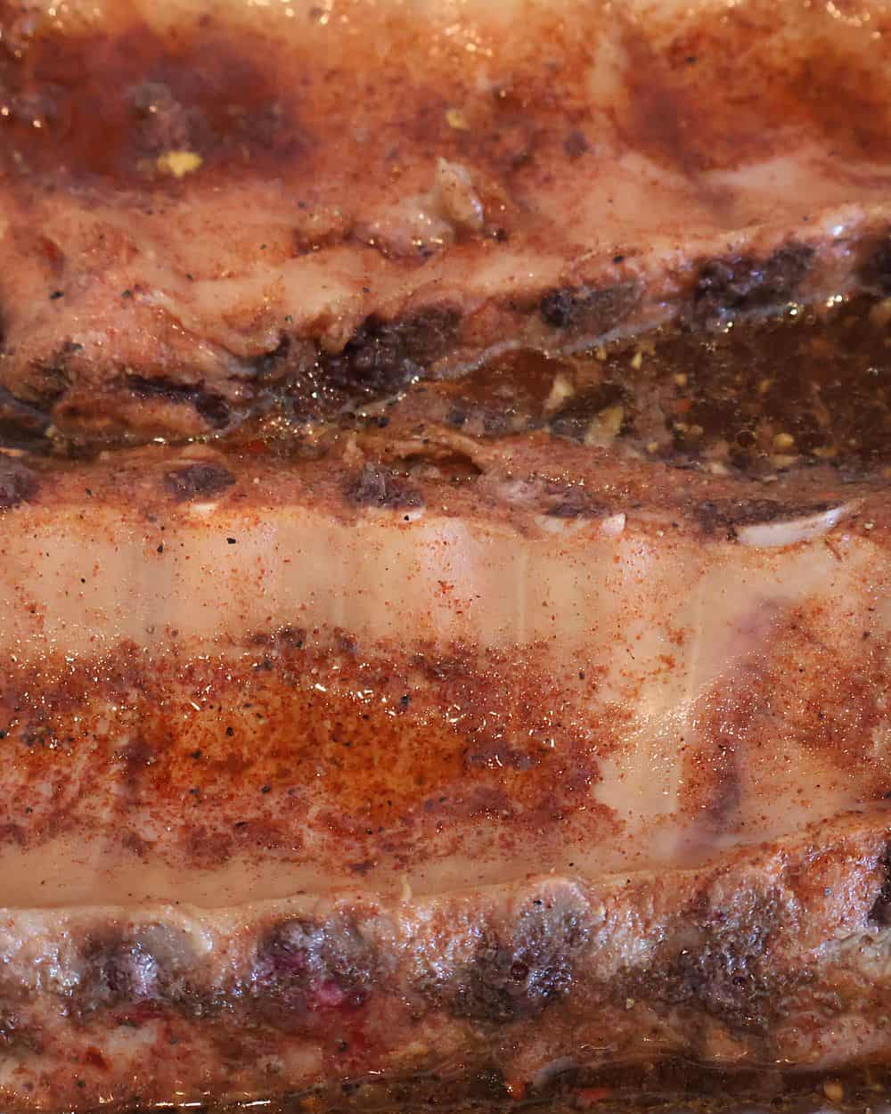 Flipping tender braised ribs with tongs, steam rising from the tray