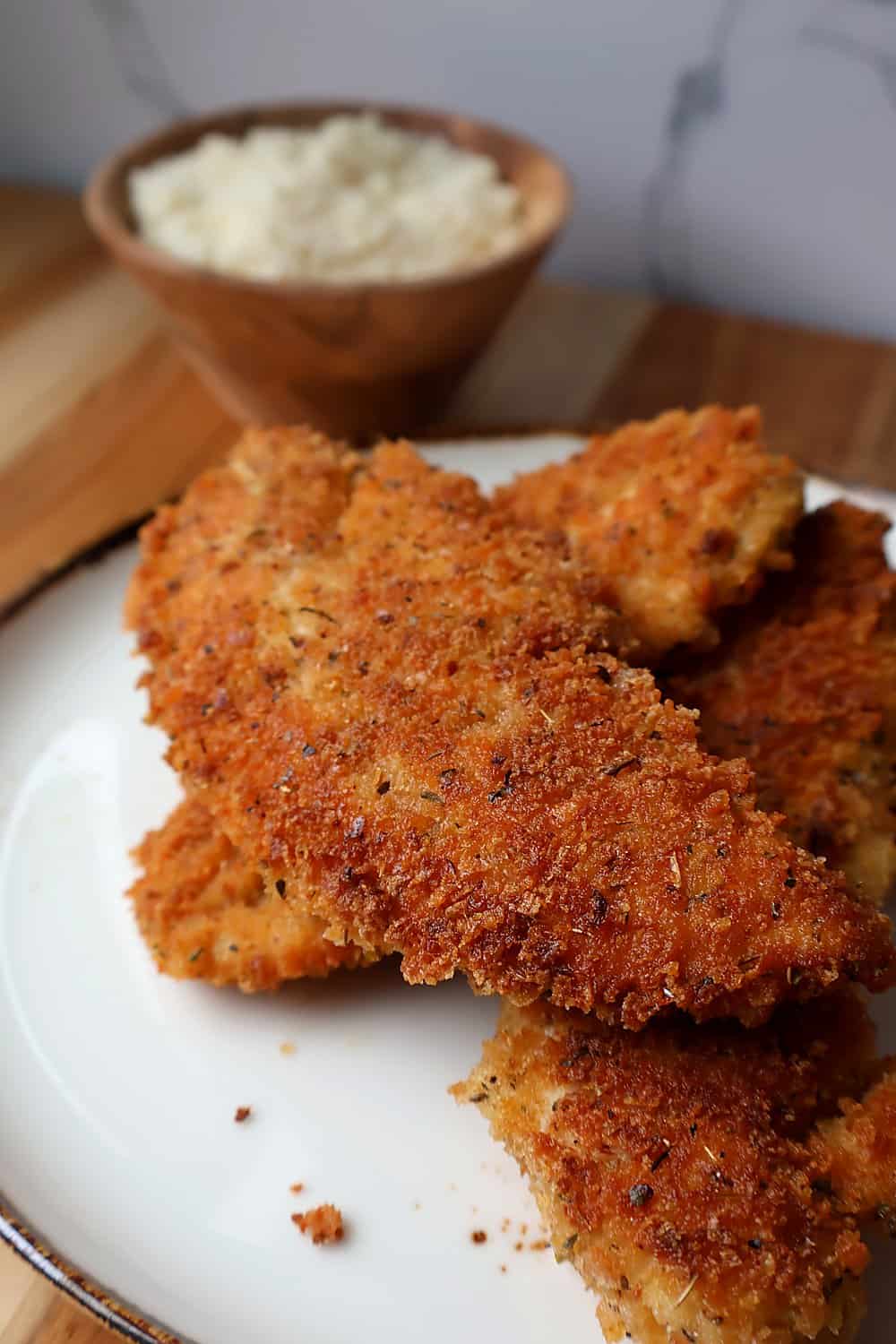 Crispy parmesan chicken tenders sliced and stacked, showing the golden craggy crust