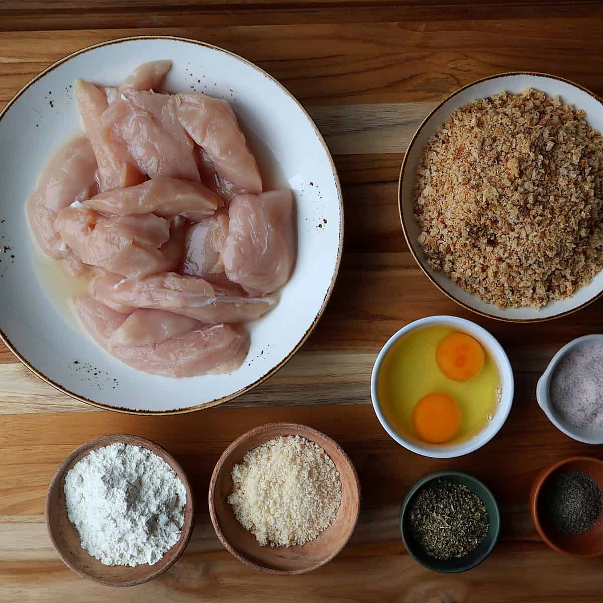 Ingredients for parmesan chicken tenders laid out in small bowls