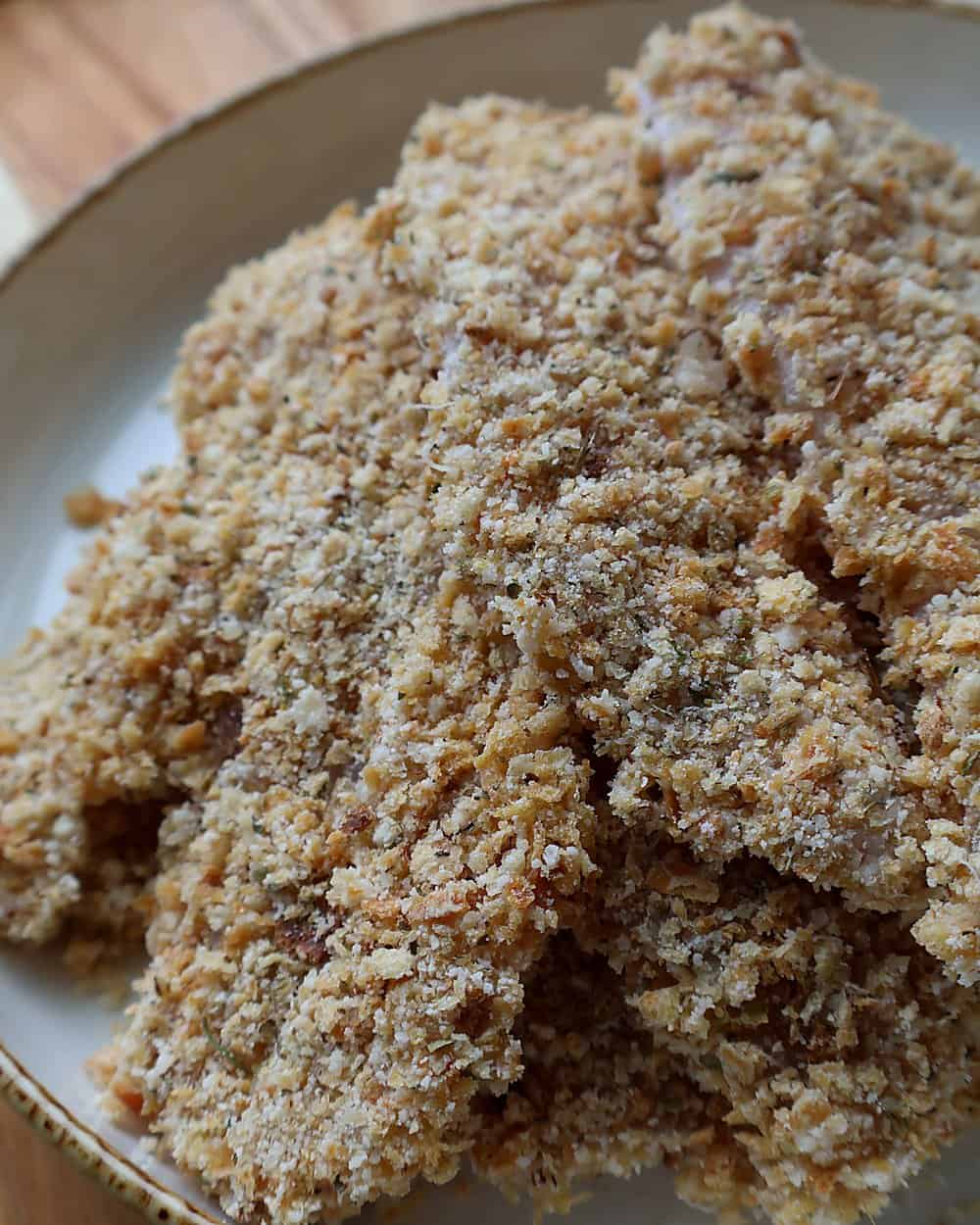 Pressing parmesan breadcrumb mixture onto a chicken tender