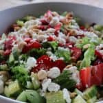 Strawberry salad recipe with fresh strawberries, gorgonzola cheese, cucumber, and candied almonds drizzled with strawberry balsamic dressing