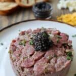 Beef tartare appetizer with caviar and chives plated with accoutrements