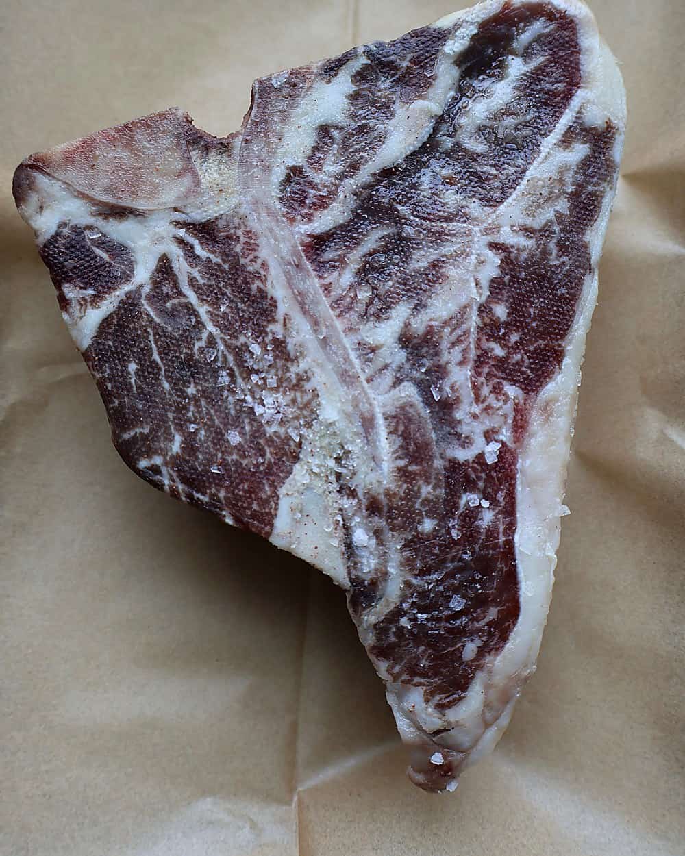 3-inch dry aged porterhouse on a wire rack in a 225°F oven with a leave-in probe in the strip side, then tented under foil while a cast iron skillet smokes on the cooktop