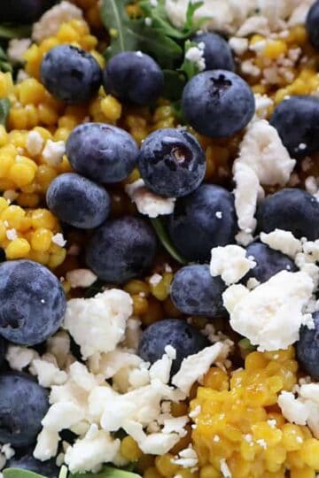 Israeli couscous salad with blueberries, arugula, and feta in a bowl - featured image
