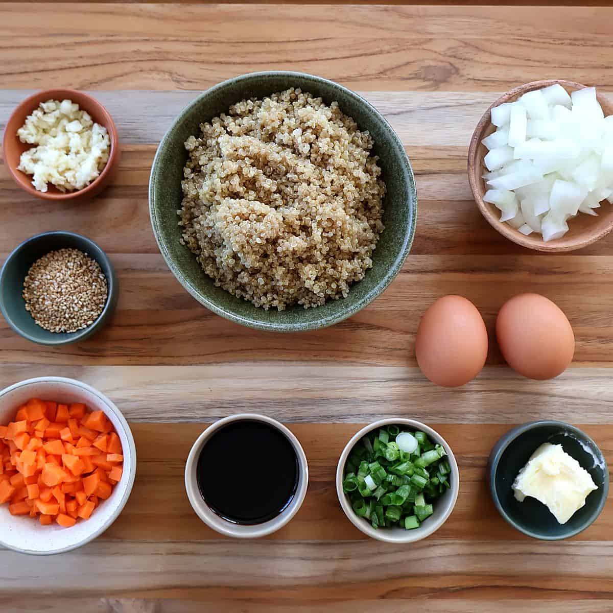 Ingredients for quinoa fried rice laid out on a wood board