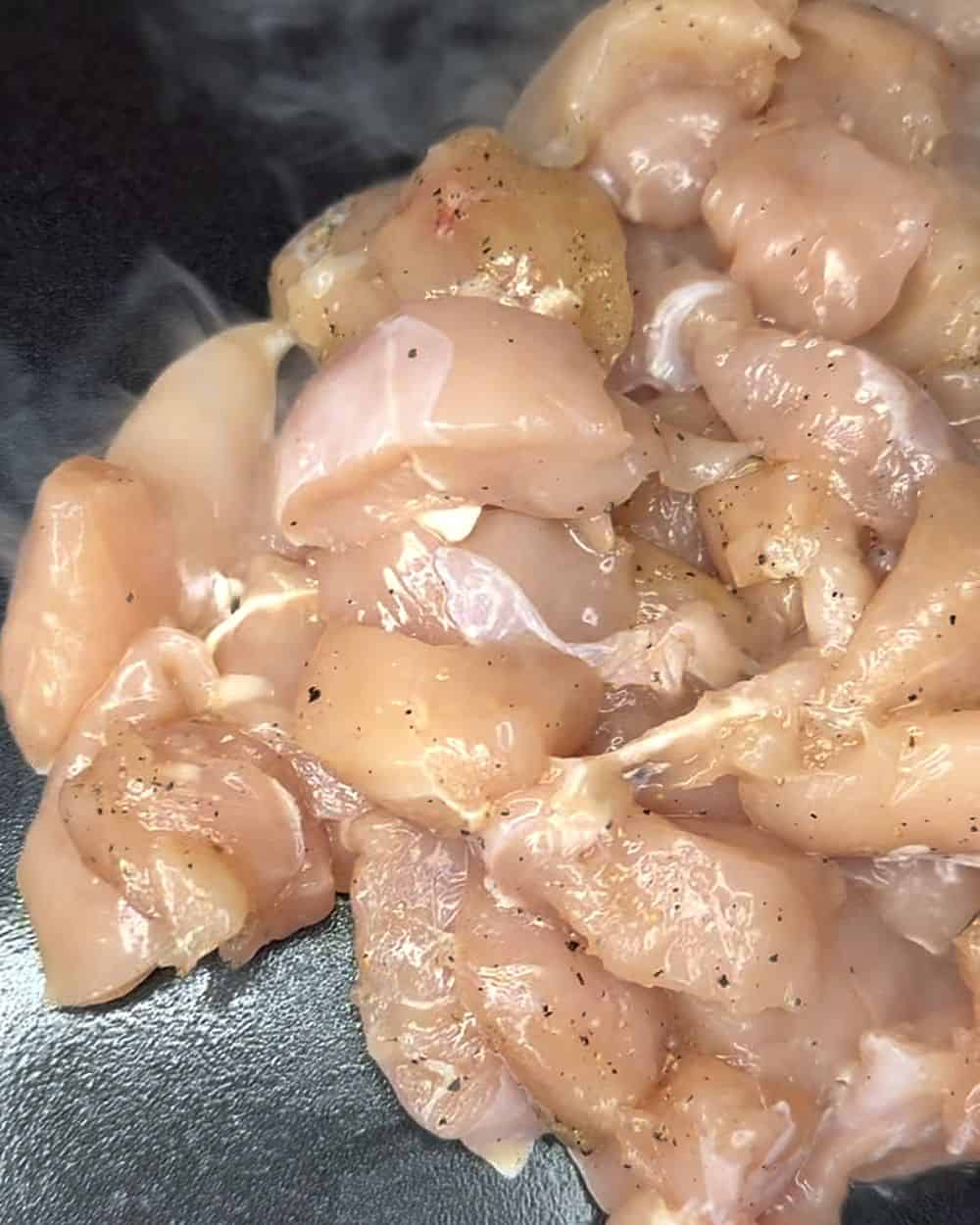 Seasoned bite-size chicken searing in a pan