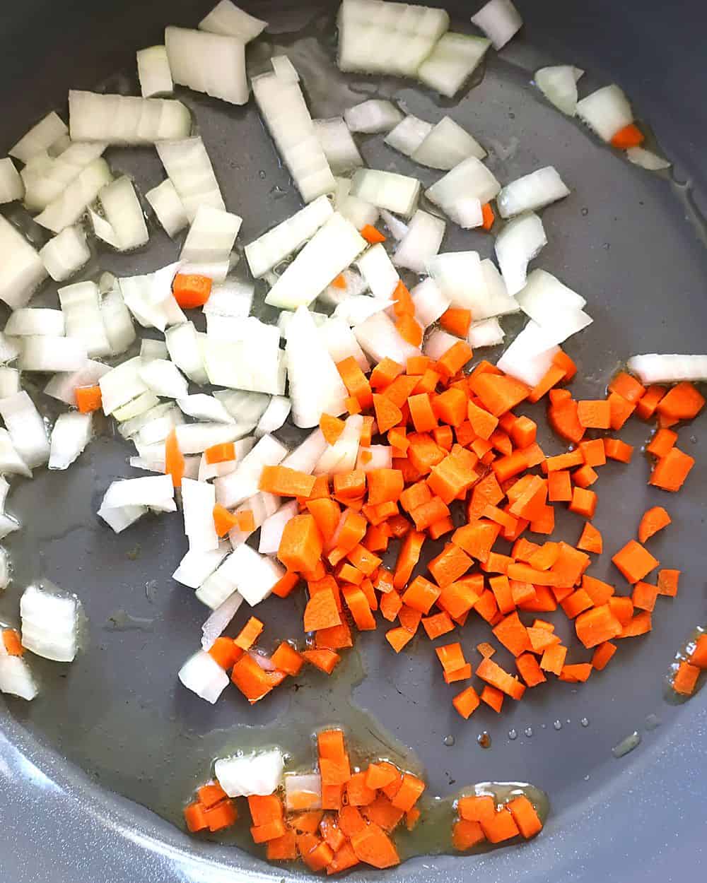Diced onion and carrot softening in a pan