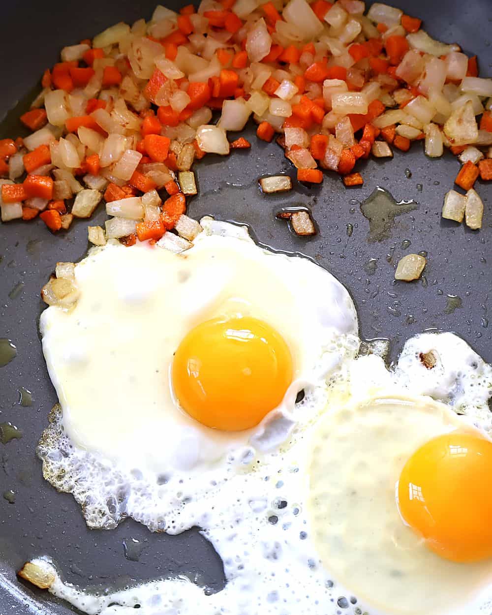 Eggs cracked into the pan with the vegetables