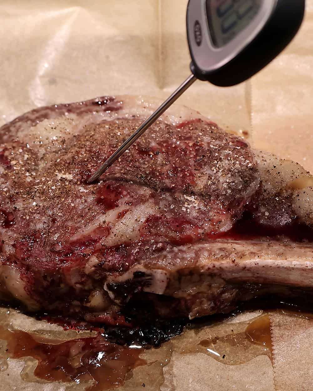 Instant-read thermometer inserted into a tomahawk ribeye to check internal temperature