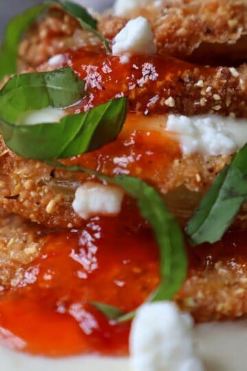Southern fried green tomatoes stacked with whipped goat cheese, red pepper jelly, and fresh basil