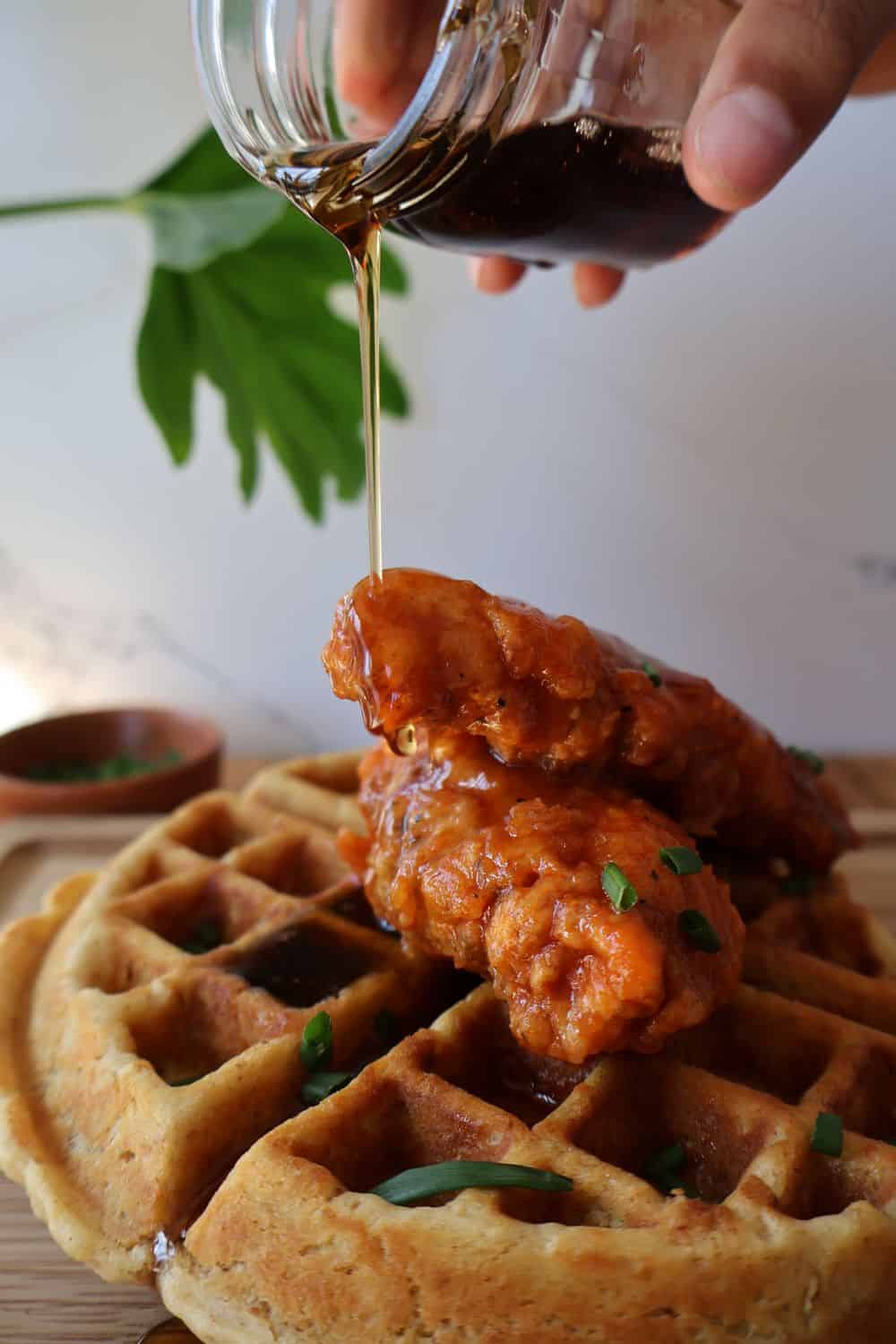 Spicy chicken and waffles topped with maple syrup and chives — finished plate hero image