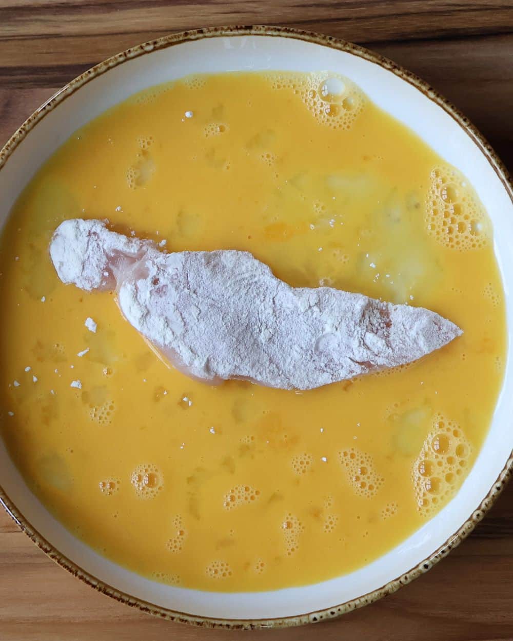 Prepared dredging station with seasoned flour and beaten eggs in shallow bowls