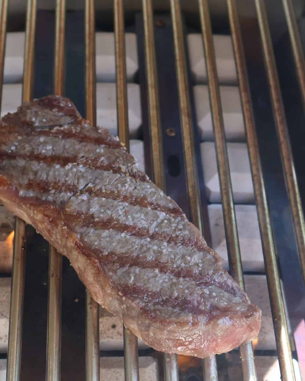 Wagyu strip with dark grill marks finishing on the cool side of the grill