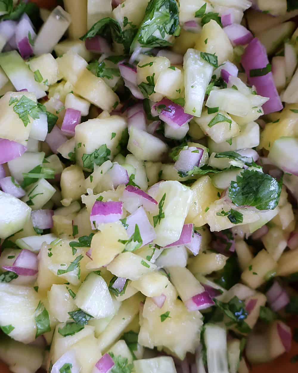 Fresh pineapple salsa with cucumber, red onion, and cilantro in a bowl