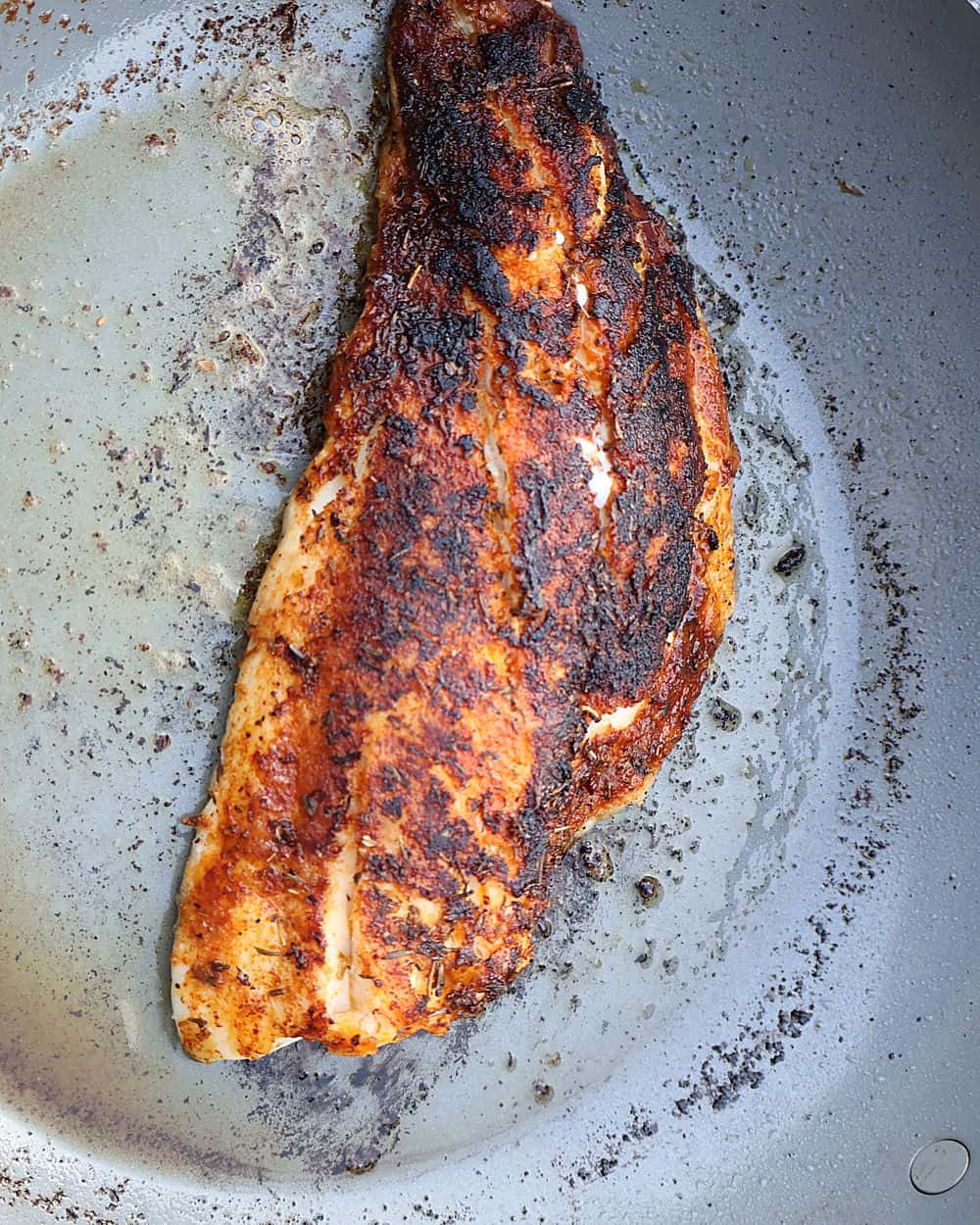 Blackened fish searing in a hot skillet