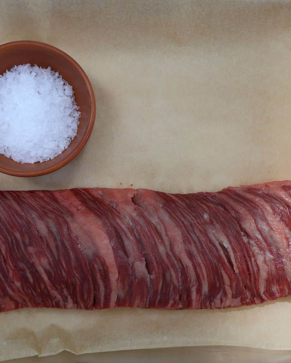 Wagyu skirt steak patted dry and seasoned with kosher salt and pepper on a board