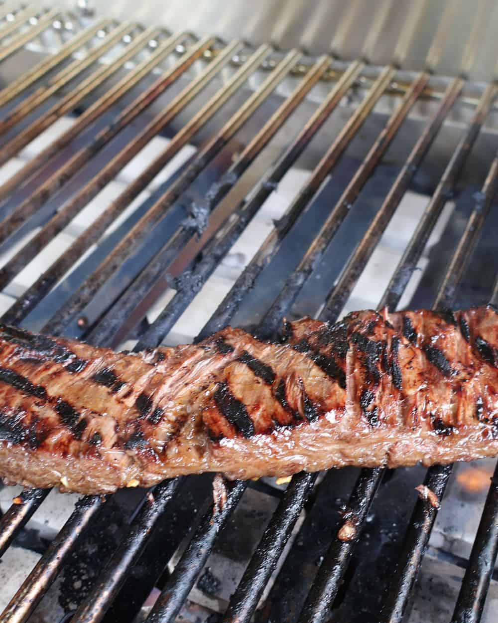 Wagyu skirt steak searing over a hot grill with a deep brown char forming