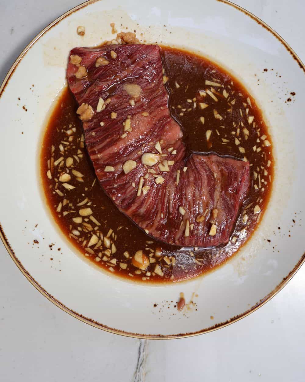 Wagyu skirt steak marinating in the miso marinade with garlic