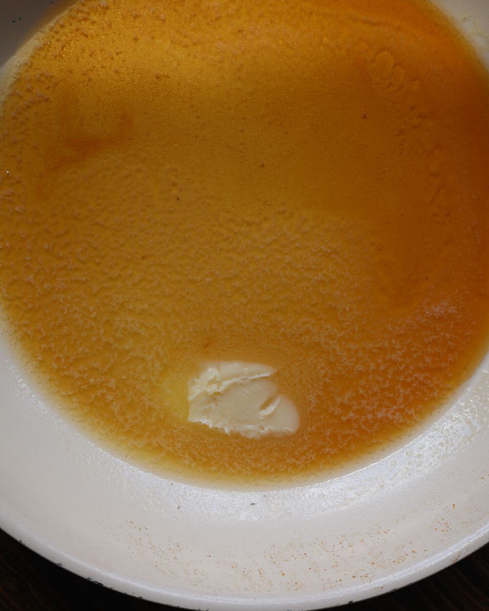 Butter melting into hot honey glaze in a pan