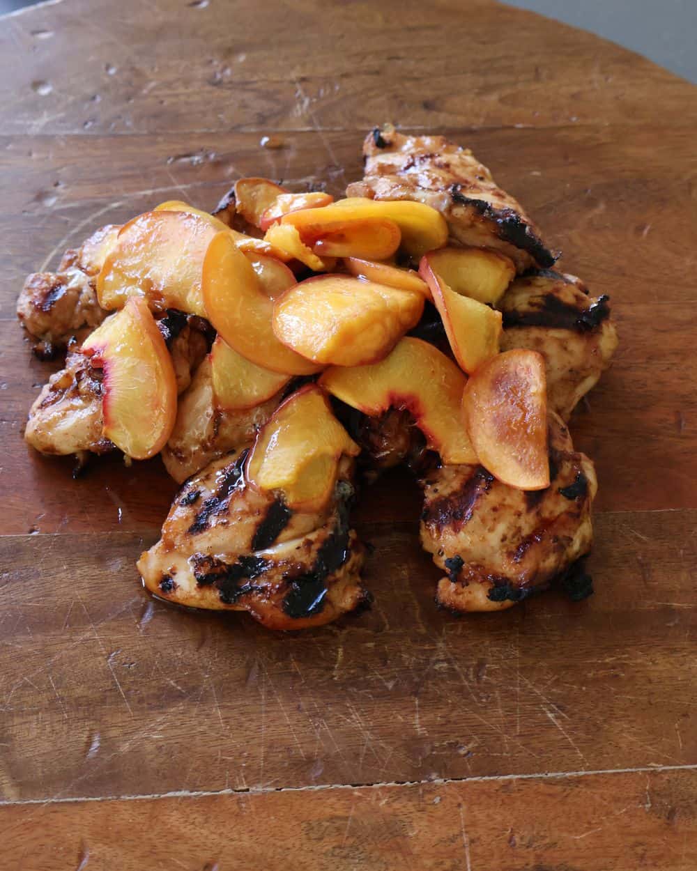 Plated hot honey chicken topped with charred peaches and hot honey drizzle