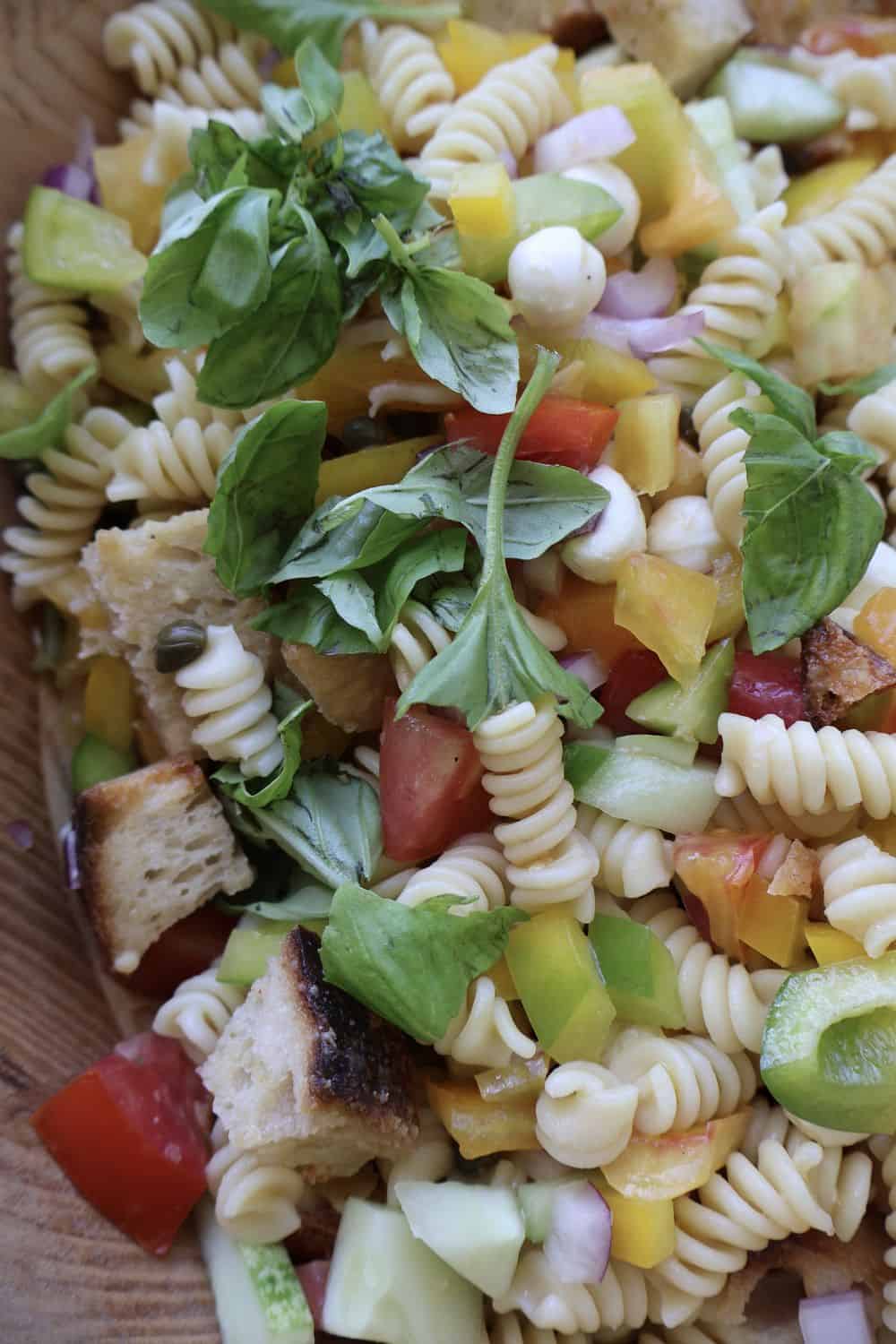 Overhead flat-lay of finished panzanella pasta salad with heirloom tomatoes and basil