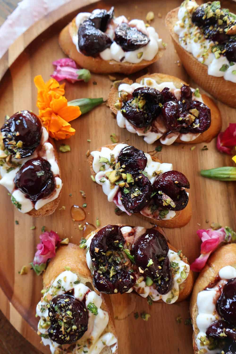 Cherry bruschetta with balsamic roasted cherries and whipped ricotta on a wood serving board