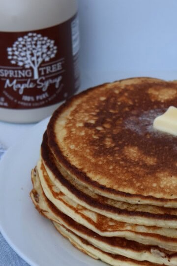 A stack of high protein cottage cheese pancakes on a white plate with butter melting on top