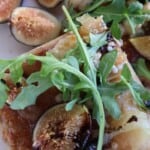 Fig gorgonzola flatbread cut into pieces with fresh figs, arugula and balsamic drizzle